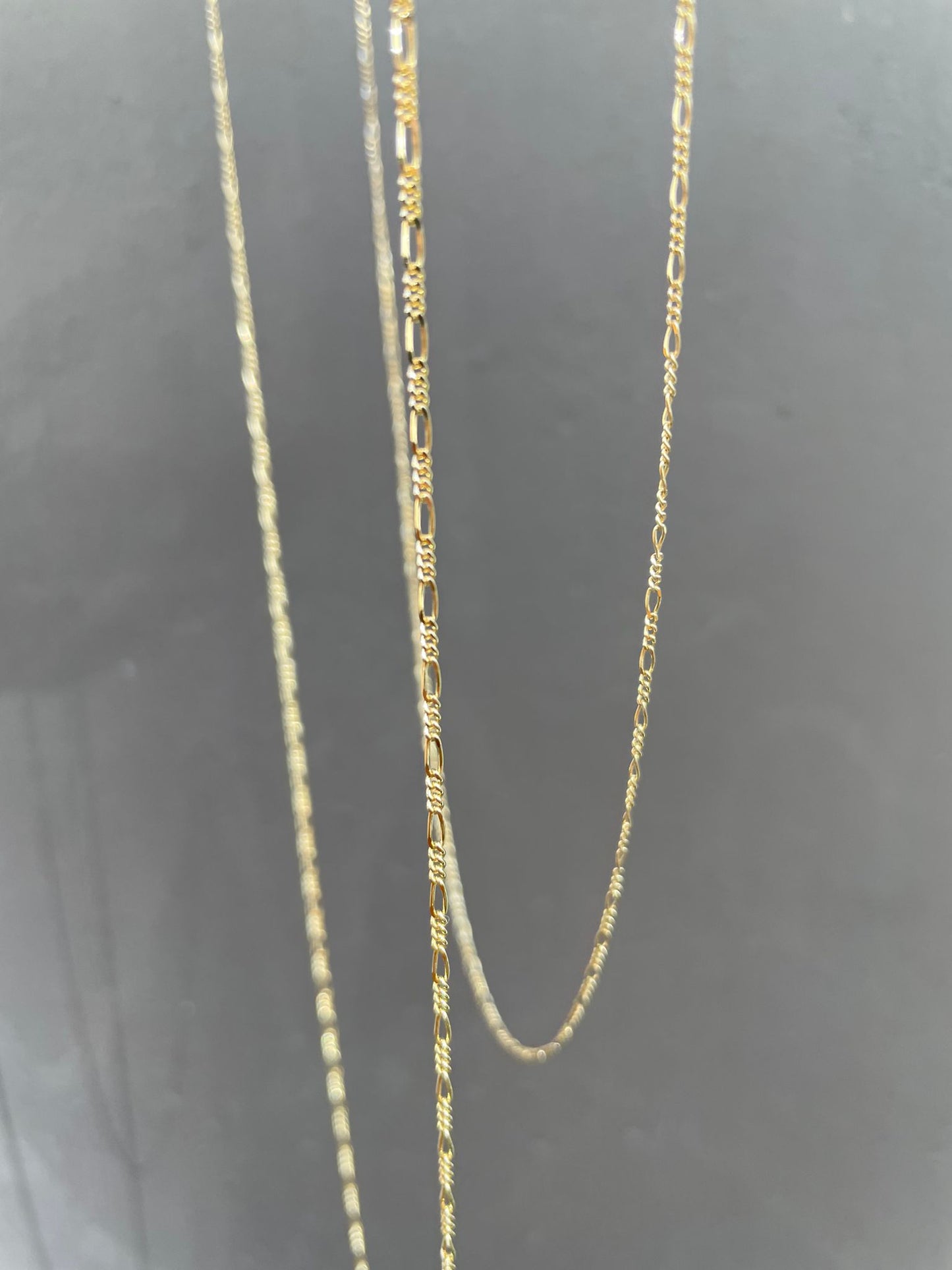 18 karat gold Figaro chain. The chain features an alternating pattern of elongated oval links and shorter round links. It is available in a variety of lengths.
