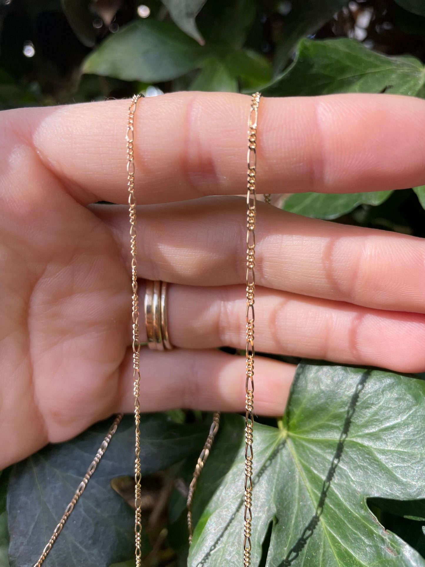 18 karat gold Figaro chain. The chain features an alternating pattern of elongated oval links and shorter round links. It is available in a variety of lengths.