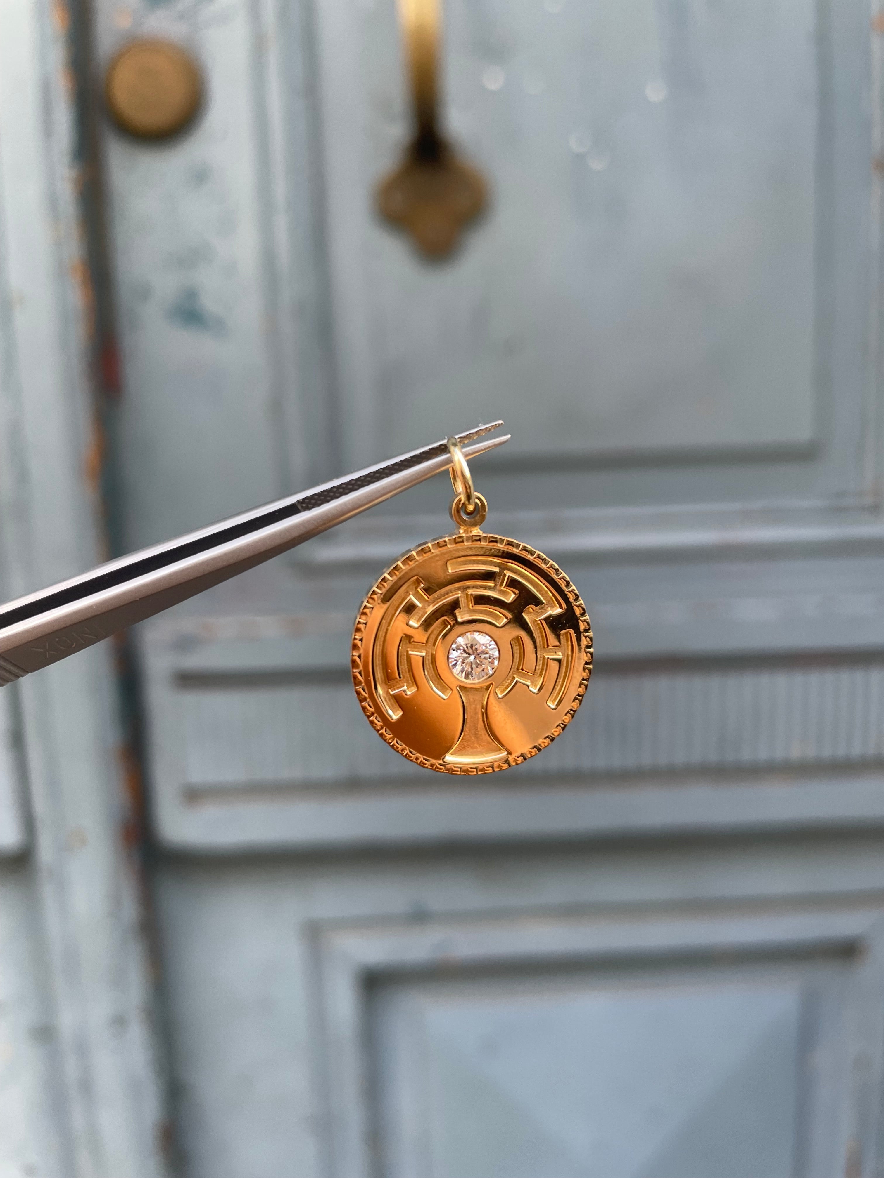 a pendant in gold, with a diamond in the middle. It shows the tree of life, like a maze.
