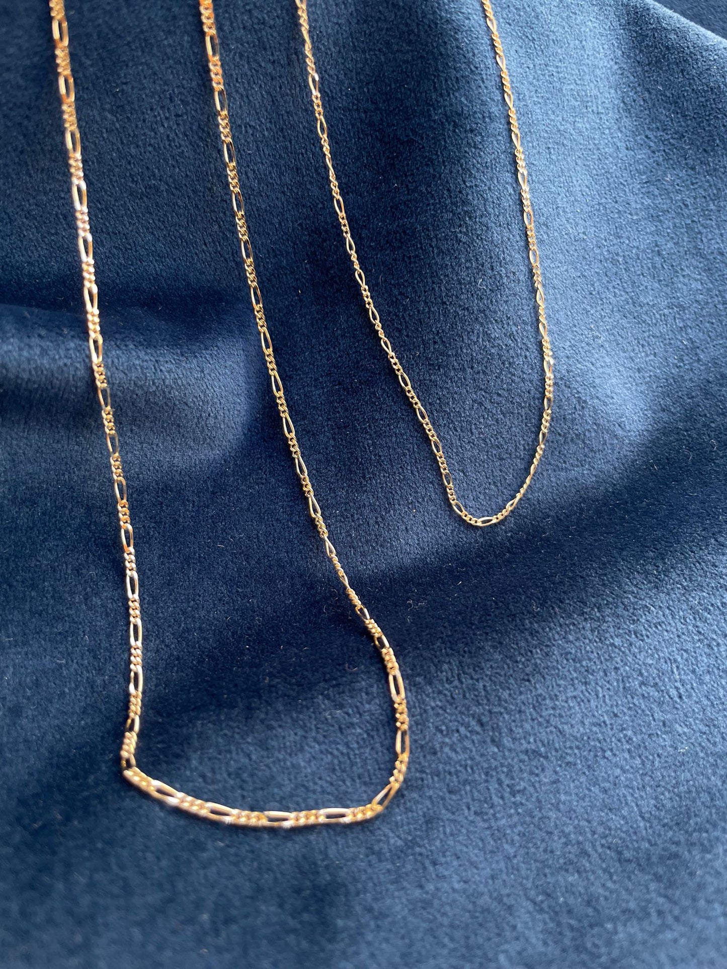 18 karat gold Figaro chain. The chain features an alternating pattern of elongated oval links and shorter round links. It is available in a variety of lengths.