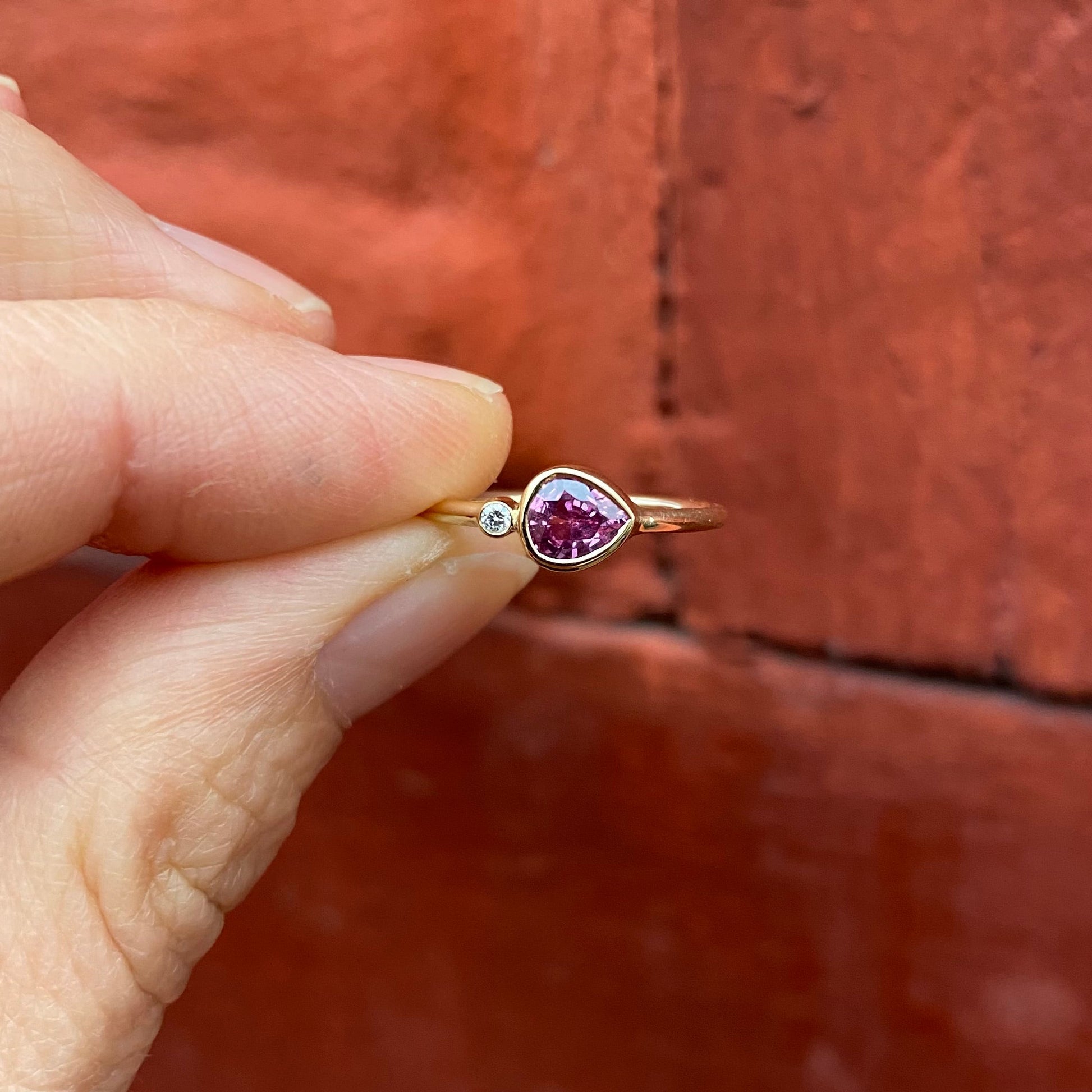 The picture features a pink sapphire ring in a brilliant cut. On the ring is also a round diamond.